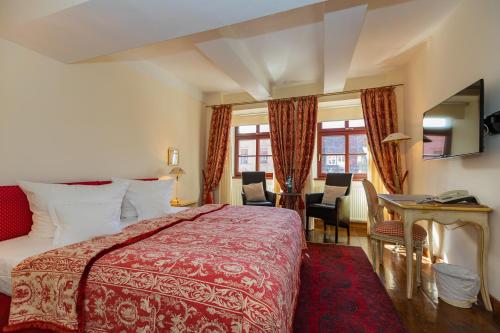 a hotel room with a bed and a table and chairs at Hotel Zum Bär in Quedlinburg