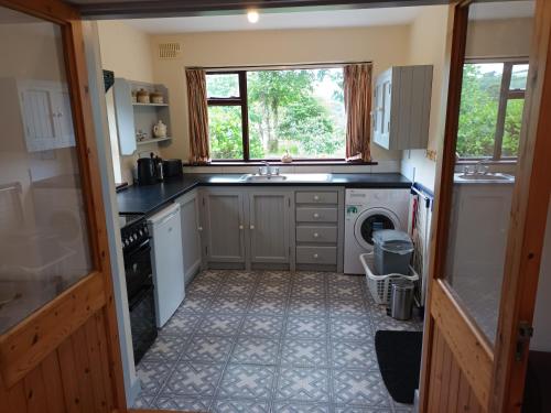 a kitchen with a sink and a washing machine at Sea view 1-Bed Cottage with private garden in Skibbereen