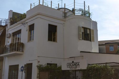 a white building with a sign in front of it at Locanda Popolare in Aci Castello