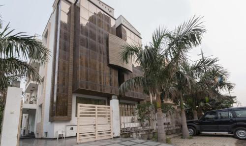 a building with palm trees in front of it at Treebo Trend House Inn in Noida