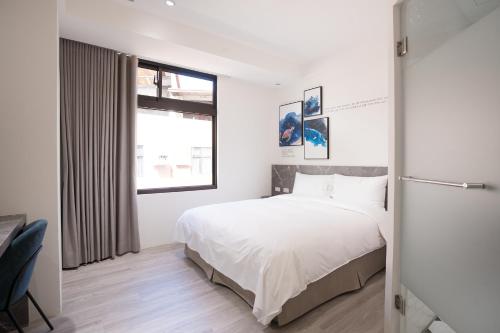 a bedroom with a white bed and a window at The Way Inn in Taichung