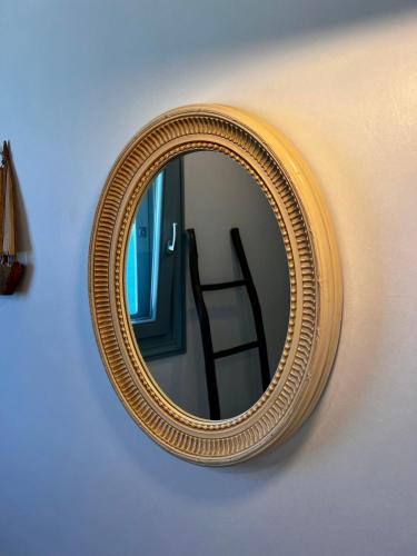 a gold mirror on a wall with a chair in it at Casa Bianca of Kea in Melissaki