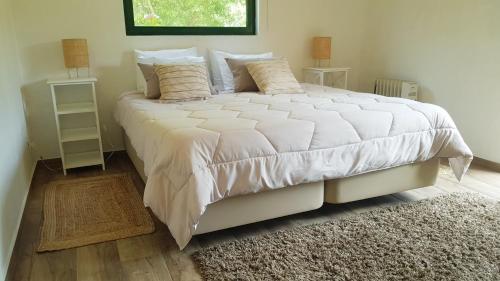 a bedroom with a large white bed with a rug at Casa da Mata in Praia de Mira