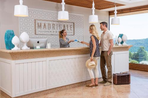 a man and woman standing at the counter of a marriott hotel at Madrigale Panoramic&Lifestyle Hotel in Costermano