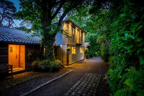 a house with a tree next to a street at Pinetum Garden Cottages in St Austell