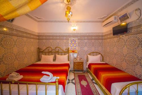 twee bedden in een slaapkamer met twee zwanen erop bij Riad Haddaji Fes in Fès