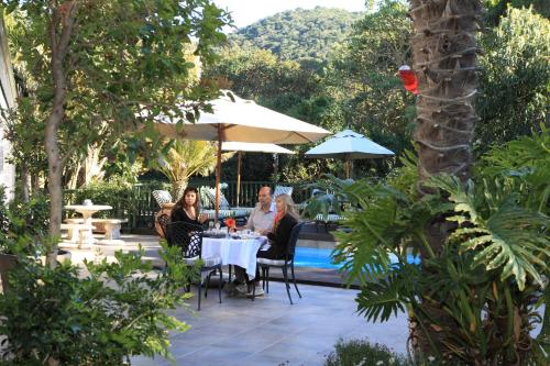 a group of people sitting at a table near a pool at Cinnamon Boutique Guest House in Wilderness