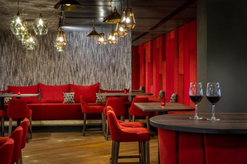 a restaurant with red chairs and tables and wine glasses at Hotel FrechDachs in Bad Füssing