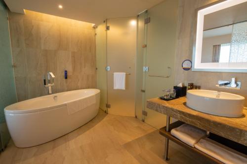 a bathroom with a large tub and a sink at Novotel Pune Viman Nagar Road in Pune