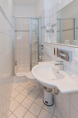 a white bathroom with a sink and a shower at Hotel Zum Bär in Quedlinburg