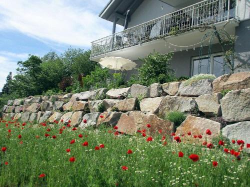 a stone wall with red flowers in front of a building at Schöne Zeiten Ferienwohnung in Baiersbronn