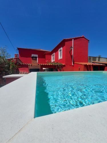 a house with a swimming pool in front of a red house at Sotam Country House in Góis