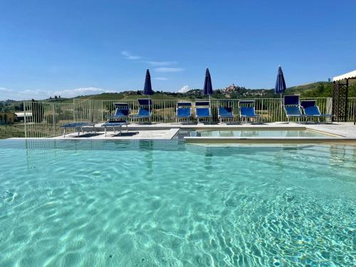 Una piscina de agua con sillas azules. en Agriturismo La Mussia en Castelnuovo