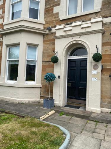 a house with a black door and a potted plant at Ellwyn House in Edinburgh