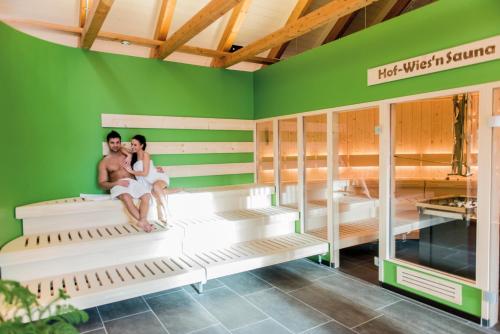 a couple sitting on beds in a sauna at Hotel am Haslinger Hof in Bad Füssing