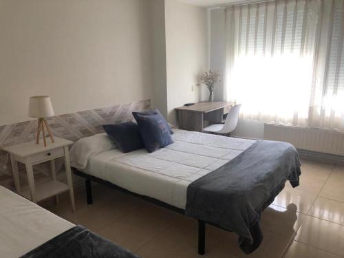 a bedroom with a bed and a desk and a window at Pensión Cantabrico in Navia
