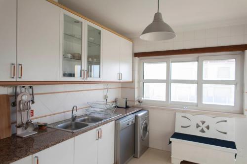 eine Küche mit weißen Schränken, einem Waschbecken und einem Fenster in der Unterkunft Middle of the bay 2 bedroom apartment in Ferrel