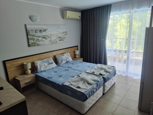 a bedroom with a bed and a large window at Park and pool Studio Apostolovi in Nesebar