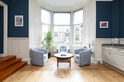 a living room with blue walls and a table and chairs at JOIVY Haymarket in Edinburgh