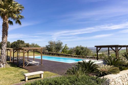 a pool at a villa with a palm tree at Masseria del Carrubo in Noto