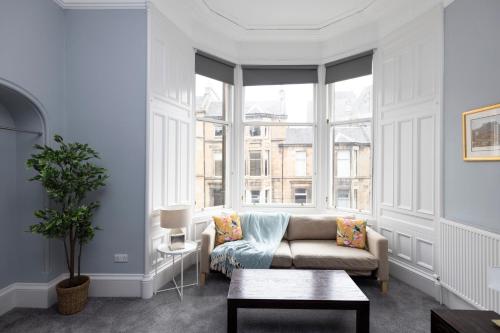 a living room with a couch and a large window at JOIVY Haymarket in Edinburgh