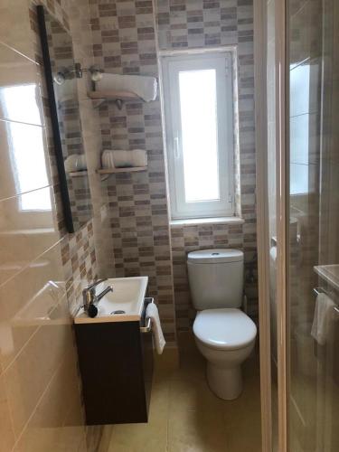 a bathroom with a toilet and a sink and a window at Pensión Cantabrico in Navia
