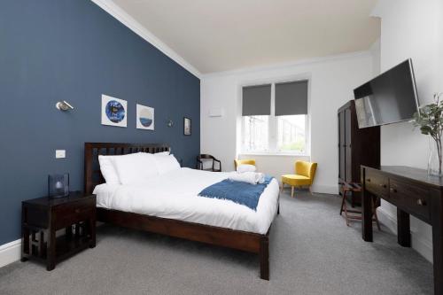 a bedroom with a bed and a blue wall at JOIVY Haymarket in Edinburgh