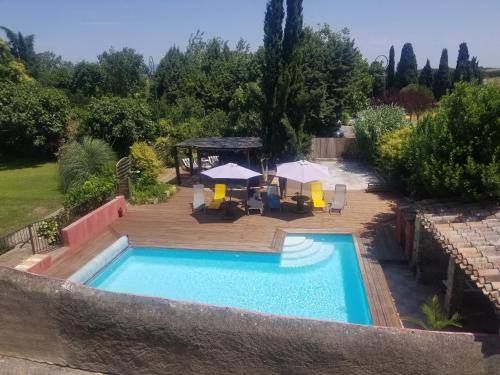 a swimming pool with a table and umbrellas in a yard at Domaine du Prieuré Couvent & Presbytère in Carcassonne