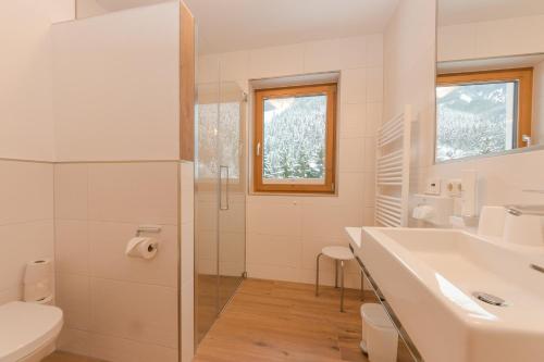 a white bathroom with a sink and a shower at Hotel Oberwirt - nahe an Saalbach und Zell am See, Viehhofen Sommercard in Viehhofen