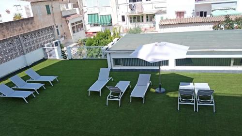 a patio with chairs and an umbrella on the grass at Hotel Abelay in Palma de Mallorca