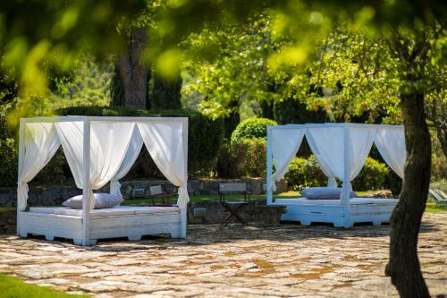 two white beds in a park with trees at Country Relais La Mortella in Porto Ercole