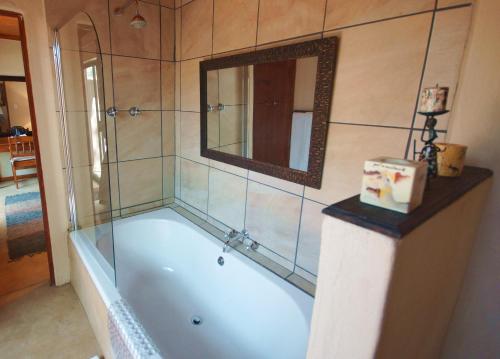 eine Badewanne im Bad mit Spiegel in der Unterkunft Kruger River Holiday Home in Marloth Park