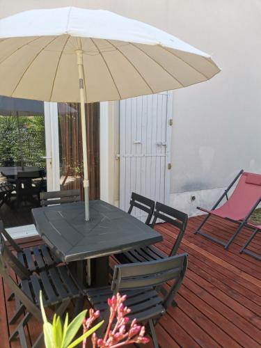 a table and chairs with an umbrella on a deck at BASTIDON EN PROVENCE in Aubignan