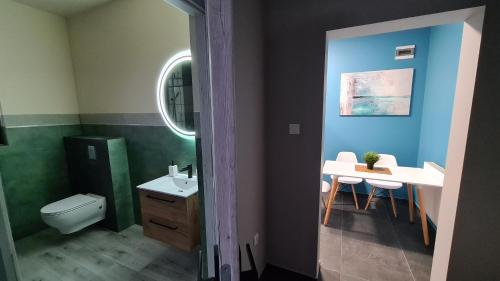 a bathroom with a toilet and a sink and a table at Urocze Apartamenty na Wsi in Golędzinów