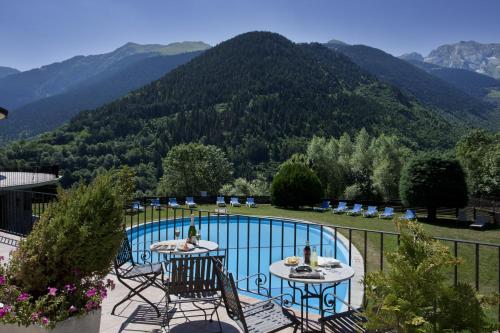 un patio con piscina, sillas y montañas en Parador de Vielha en Vielha