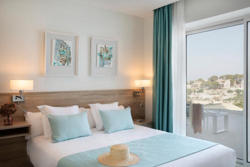 a bedroom with a large bed with a large window at Aparthotel Marina Drach in Porto Cristo