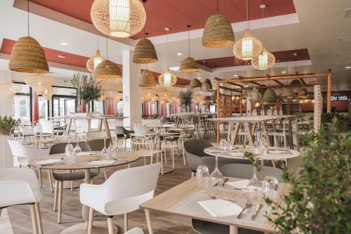 un restaurant avec des tables, des chaises et des lustres dans l'établissement Belambra Clubs Port Camargue - Les Salins, au Grau-du-Roi