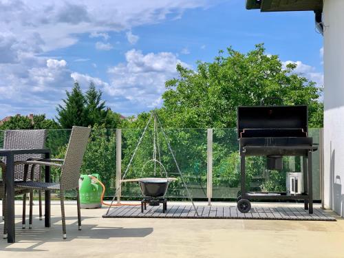 a patio with a grill and a piano and chairs at Thermal Apartman - EM in Gárdony