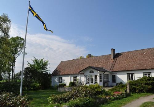 een wit huis met een vlag ervoor bij Rusthållaregården i Edenryd in Bromölla