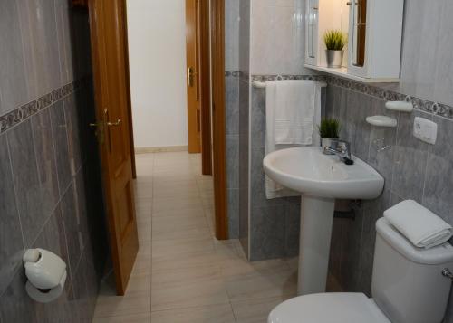 een badkamer met een witte wastafel en een toilet bij Raxó con piscina en la urbanización in Raxo