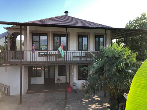 una casa con un balcón con dos banderas. en Vse Dlya Vas Guest House, en Gudauta