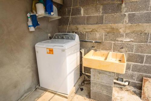 a washing machine in a room with a brick wall at DepaB privado, centrico,Wifi 80 mb ,aire acondicionado ,cocina, cochera techada, in Ciudad Valles