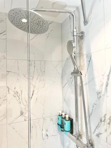 a shower in a bathroom with white marble at Karl Johan Hotel in Oslo