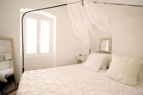 Dormitorio blanco con cama con dosel y espejo en Romantic gemstone in Pigna, en Pigna