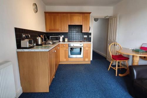 a small kitchen with wooden cabinets and a table at Stylish, comfortable apartment with balcony in Plymouth