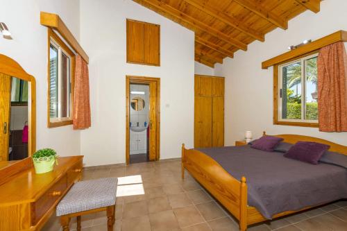 Schlafzimmer mit einem Bett, einem Schreibtisch und Fenstern in der Unterkunft Villa Iriss by Villa Plus in Polis Chrysochous