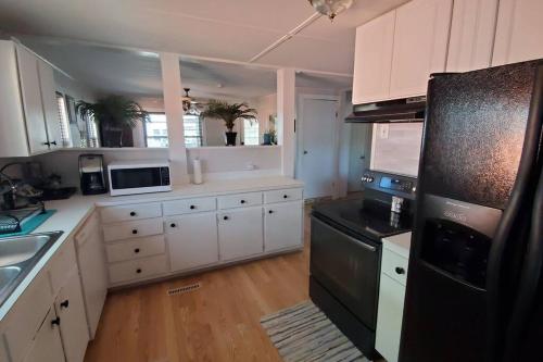 a kitchen with white cabinets and a black refrigerator at Bright and airy beach house. in Myrtle Beach