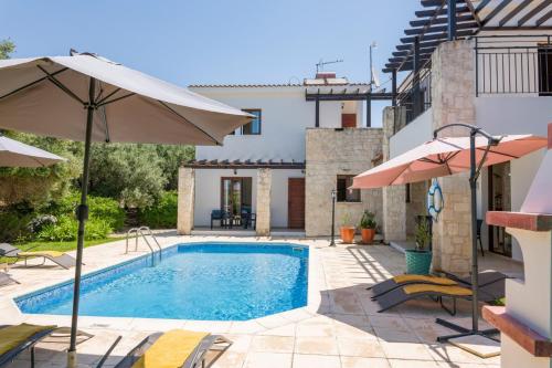 a pool with chairs and umbrellas next to a house at Villa Lena by Villa Plus in Prodhromi