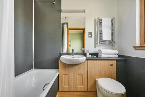 a bathroom with a tub and a sink and a toilet at Clan Macduff Hotel in Fort William