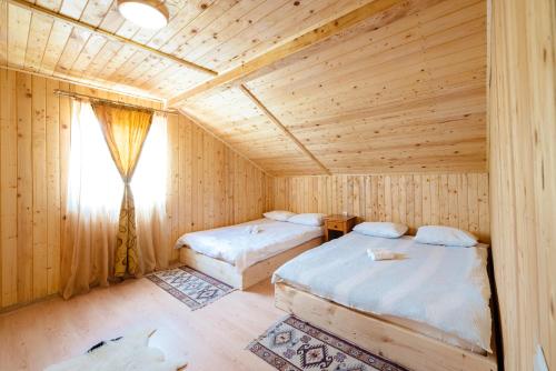 two beds in a wooden room with a window at Cabana Codreanu in Mărgău
